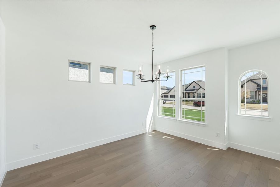Empty dining room with hardwood floors, chandelier, and large windows overlooking a neighborhood