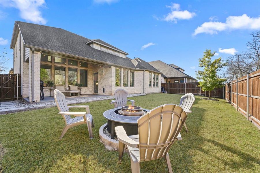 Rear view of property with an outdoor fire pit, a patio, a fenced backyard, brick siding, and roof with shingles