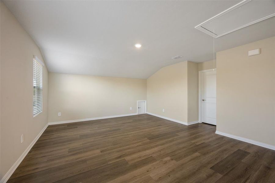 Spacious room featuring wood-finish flooring, neutral-toned walls, a window with blinds, and recessed lighting Spacious room featuring wood-finish flooring, neutral-toned walls, a window with blinds, and recessed lighting