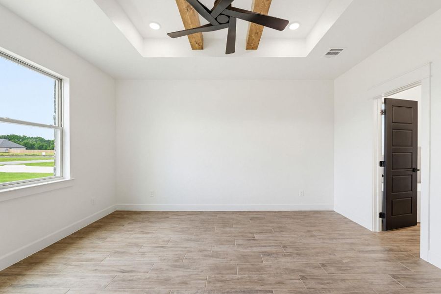 A sleek modern ceiling fan highlights this spacious room with elegant wood-look flooring. A sleek modern ceiling fan highlights this spacious room with elegant wood-look flooring.
