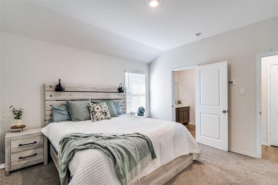 Bedroom featuring lofted ceiling, connected bathroom, baseboards, and carpet flooring