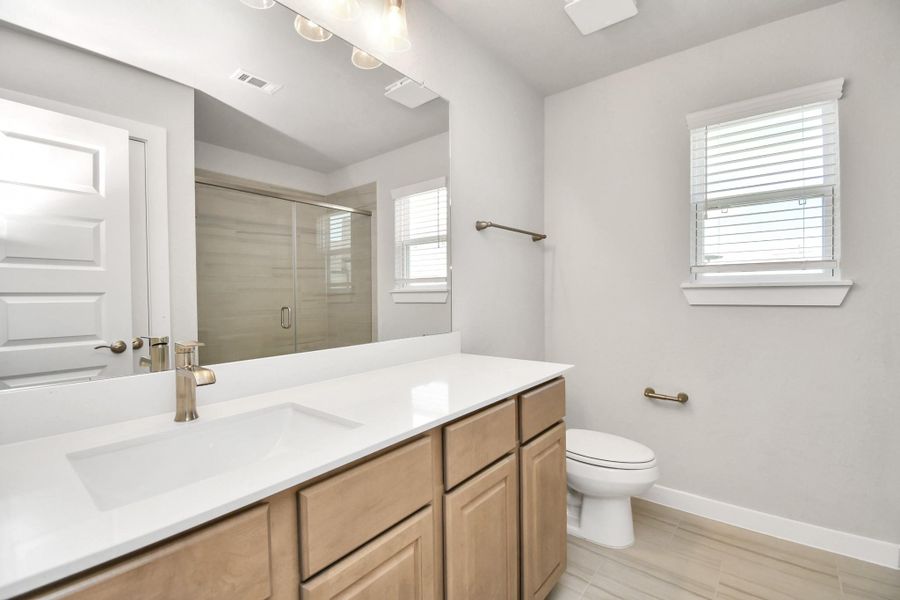 Secondary bath features tile flooring, a walk-in shower with tile surround, light stained wood cabinets, beautiful light countertop. Sample photo of completed home with similar floor plan. Actual colors and selections may vary. Secondary bath features tile flooring, a walk-in shower with tile surround, light stained wood cabinets, beautiful light countertop. Sample photo of completed home with similar floor plan. Actual colors and selections may vary.