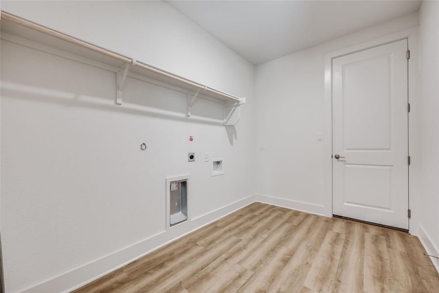 Laundry area featuring gas dryer hookup, light wood-type flooring, electric dryer hookup, and washer hookup Laundry area featuring gas dryer hookup, light wood-type flooring, electric dryer hookup, and washer hookup