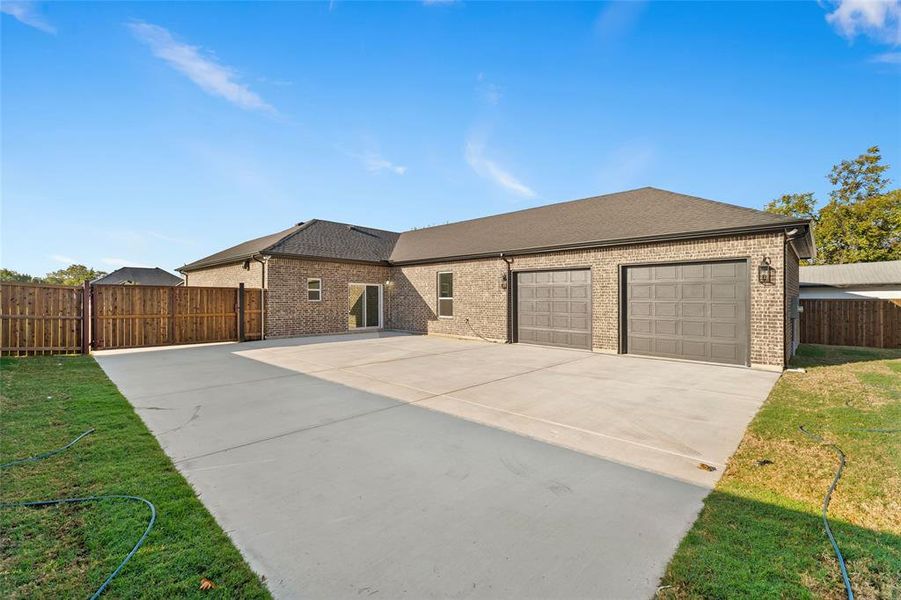 Ranch-style home featuring roof with shingles, driveway, brick siding, and a garage