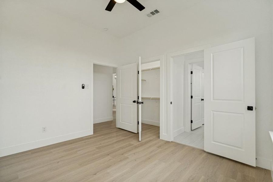 Room featuring light wood-finish flooring, white walls, and a ceiling fan Room featuring light wood-finish flooring, white walls, and a ceiling fan
