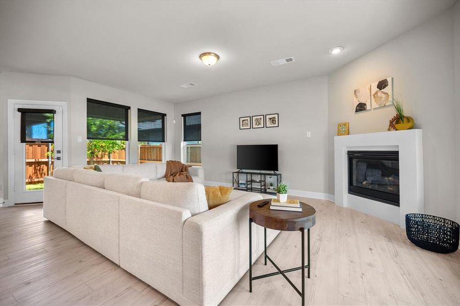 Living area featuring light wood finished floors, a glass covered fireplace, and recessed lighting Living area featuring light wood finished floors, a glass covered fireplace, and recessed lighting