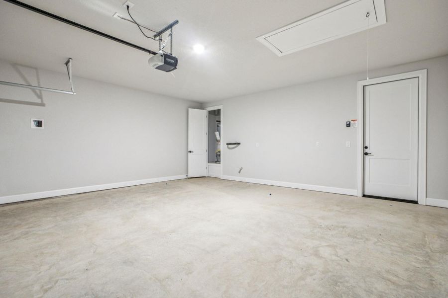 Garage with baseboards and a garage door opener Garage with baseboards and a garage door opener