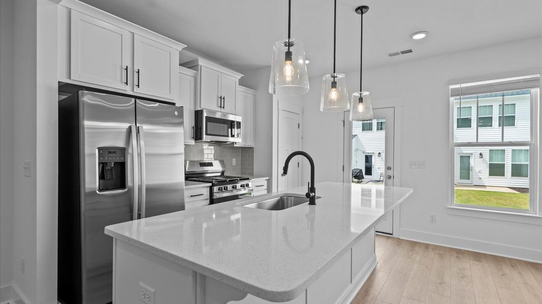 Highly skilled kitchen design includes a 9-foot island, quartz countertops, and stylish pendant fixtures Highly skilled kitchen design includes a 9-foot island, quartz countertops, and stylish pendant fixtures