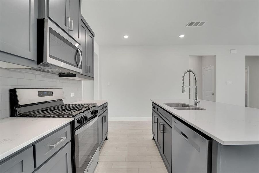 Kitchen featuring a sink, visible vents, appliances with stainless steel finishes, gray cabinets, and tasteful backsplash Kitchen featuring a sink, visible vents, appliances with stainless steel finishes, gray cabinets, and tasteful backsplash