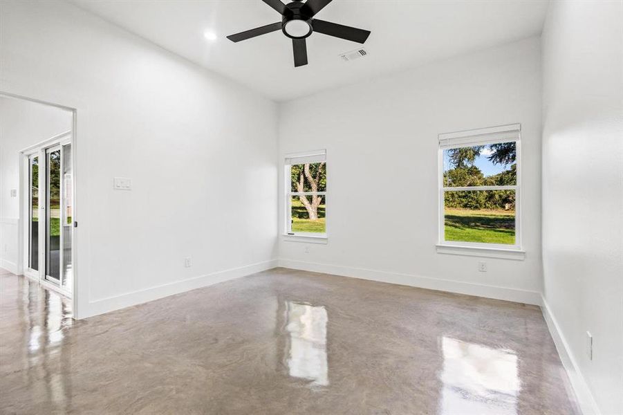 Primary bedroom with finished concrete flooring and a ceiling fan