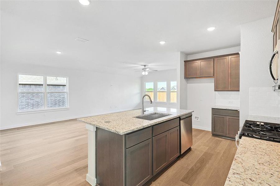 Kitchen with dishwasher, backsplash, sink, ceiling fan, and light wood-type flooring