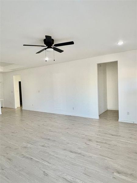Empty room with light wood-style floors and a ceiling fan