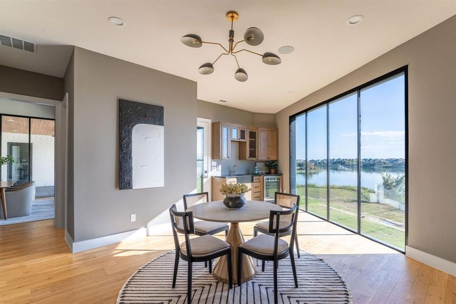 Dining room featuring light hardwood / wood-style flooring, a water view, and a healthy amount of sunlight