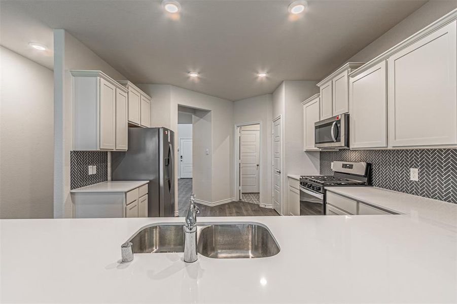 Kitchen featuring sink, appliances with stainless steel finishes, decorative backsplash, and light wood-type flooring