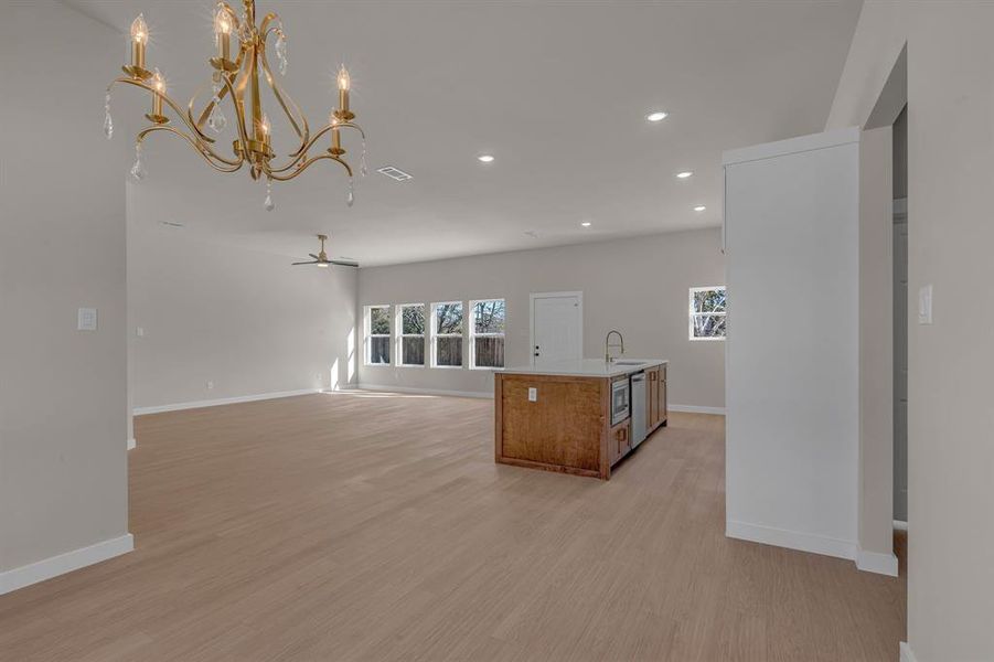 Kitchen with ceiling fan, decorative light fixtures, a kitchen island with sink, and light hardwood / wood-style flooring