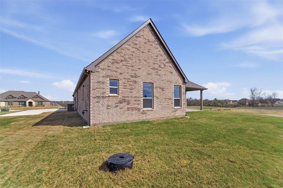 View of property exterior featuring a lawn and brick siding
