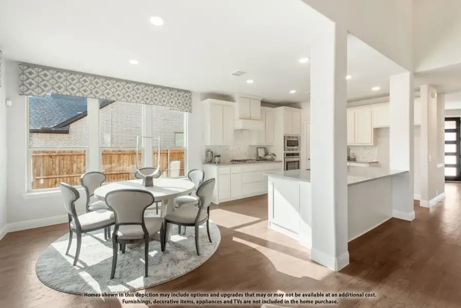Open-concept dining area and kitchen with white cabinets, hardwood floors, and round dining table for six.
