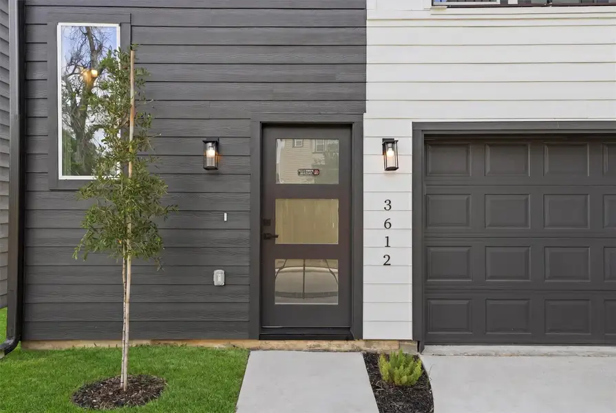 Front entry with a modern door, matching garage, and clean exterior lines. Simple landscaping adds great curb appeal.