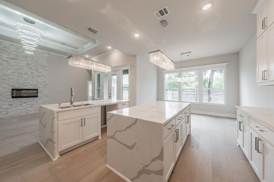 Kitchen featuring white cabinets, light stone counters, light wood-style flooring, pendant lighting, and recessed lighting