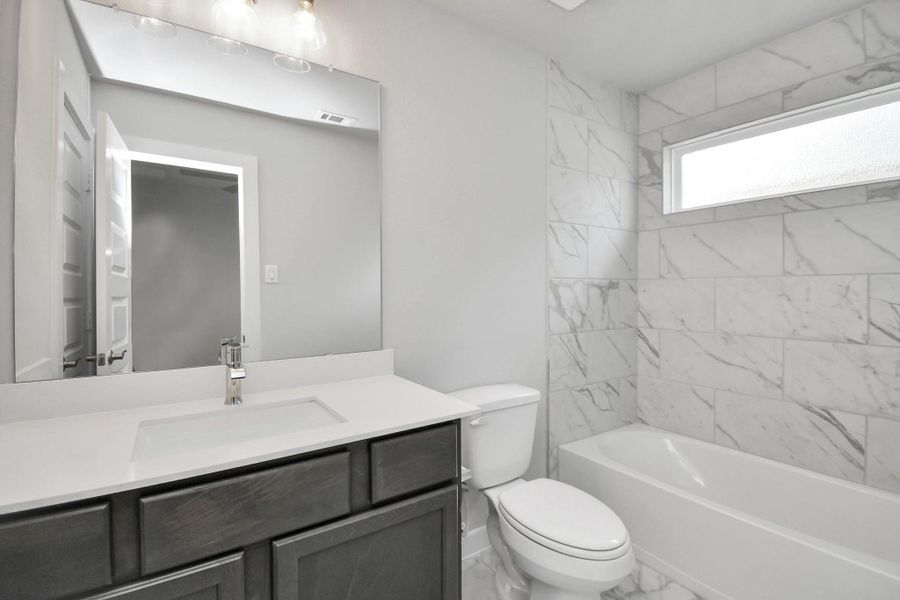 Secondary bath features tile flooring, bath/shower combo with tile surround, light stained wood cabinets, beautiful light countertop. Secondary bath features tile flooring, bath/shower combo with tile surround, light stained wood cabinets, beautiful light countertop.