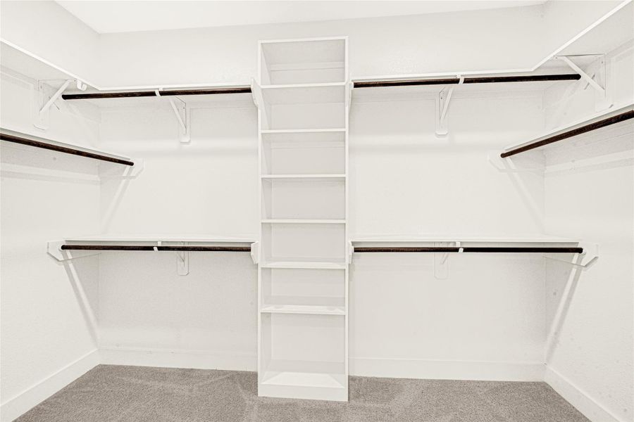 The primary en-suite is completed by this oversized walk-in closet. With multiple hanging rods and built-in shelving, there is plenty of room wardrobe organization.
