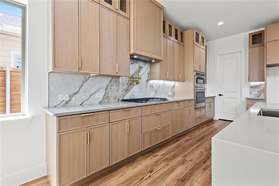 Kitchen with backsplash, appliances with stainless steel finishes, and light hardwood / wood-style floors