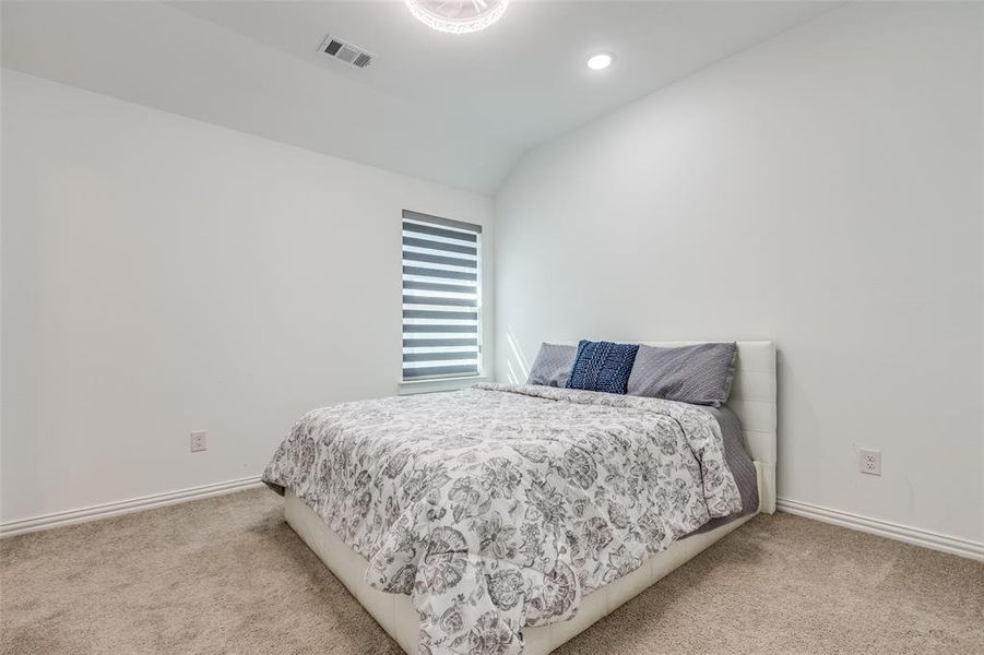 Large second floor bedroom with luxury blinds and an ensuite bathroom featuring vaulted ceiling, carpeted flooring, and luxury light /fan and recessed lighting. Large second floor bedroom with luxury blinds and an ensuite bathroom featuring vaulted ceiling, carpeted flooring, and luxury light /fan and recessed lighting.