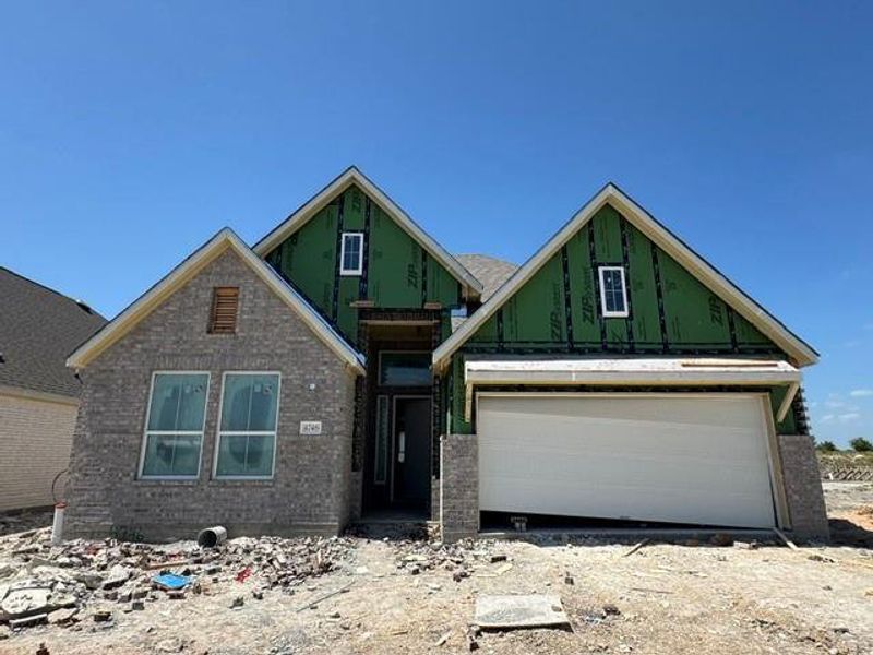 A newly constructed residence features a partial brick facade and an attached garage under a blue sky. A newly constructed residence features a partial brick facade and an attached garage under a blue sky.