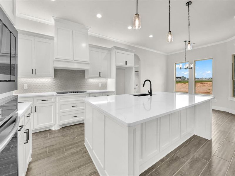 Kitchen with backsplash, white cabinets, light stone counters, wood finish floors, and ornamental molding