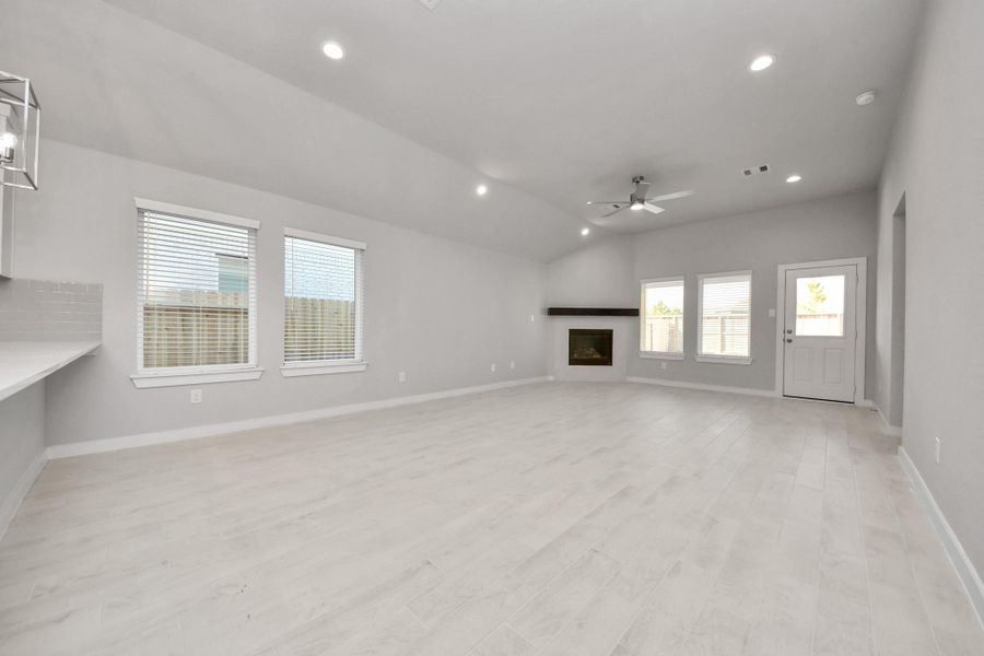 Welcome family and guests to your charming living room! With its high ceilings, recessed lighting, ceiling fan, custom paint, beautiful flooring, and large windows that let in abundant natural light, this room is perfect for gatherings. Sample photo of completed home with similar floor plan. Actual colors and selections may vary.