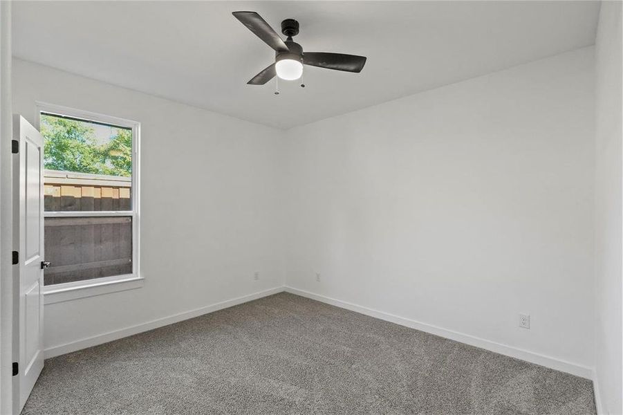 Carpeted empty room featuring ceiling fan