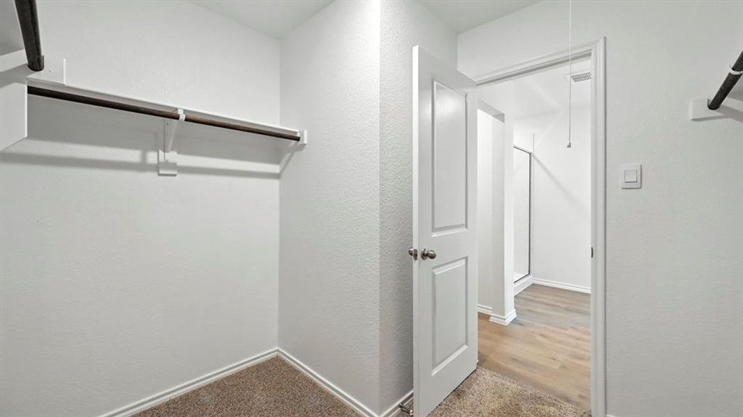 Carpeted walk-in closet with built-in shelving and hanging rod Carpeted walk-in closet with built-in shelving and hanging rod