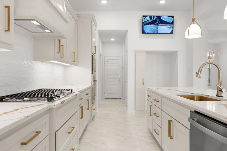 Kitchen featuring light stone counters, stainless steel appliances, white cabinetry, and pendant lighting