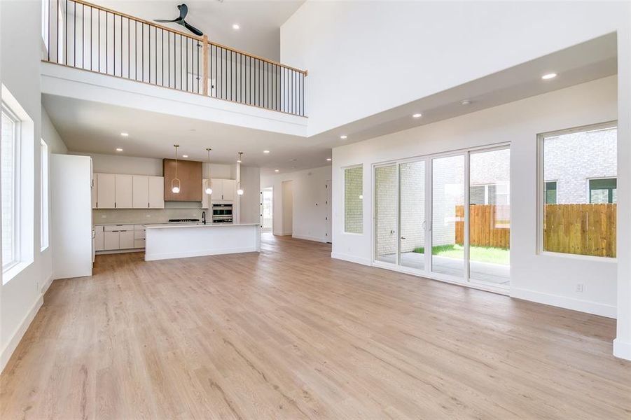 Unfurnished living room featuring a high ceiling, light wood finished floors, recessed lighting, and a ceiling fan Unfurnished living room featuring a high ceiling, light wood finished floors, recessed lighting, and a ceiling fan