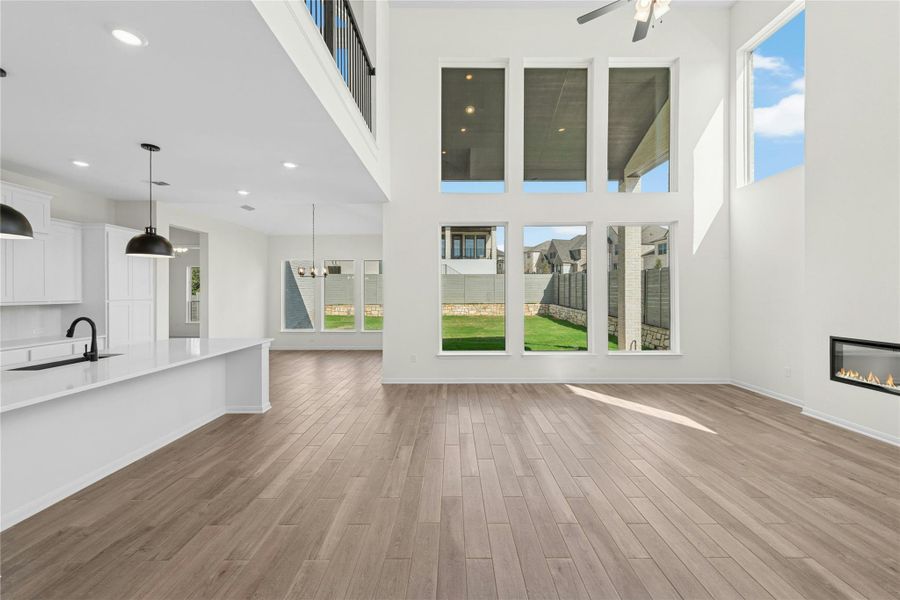 Unfurnished living room featuring a glass covered fireplace, dark wood-style floors, a towering ceiling, a ceiling fan, and recessed lighting Unfurnished living room featuring a glass covered fireplace, dark wood-style floors, a towering ceiling, a ceiling fan, and recessed lighting