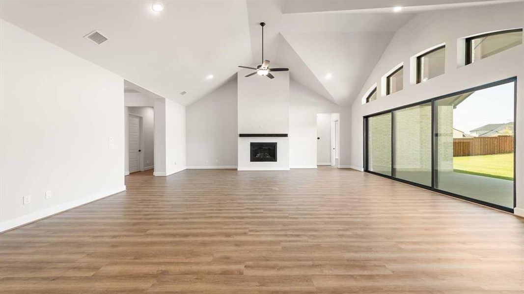 Unfurnished living room with light hardwood / wood-style floors, high vaulted ceiling, and ceiling fan