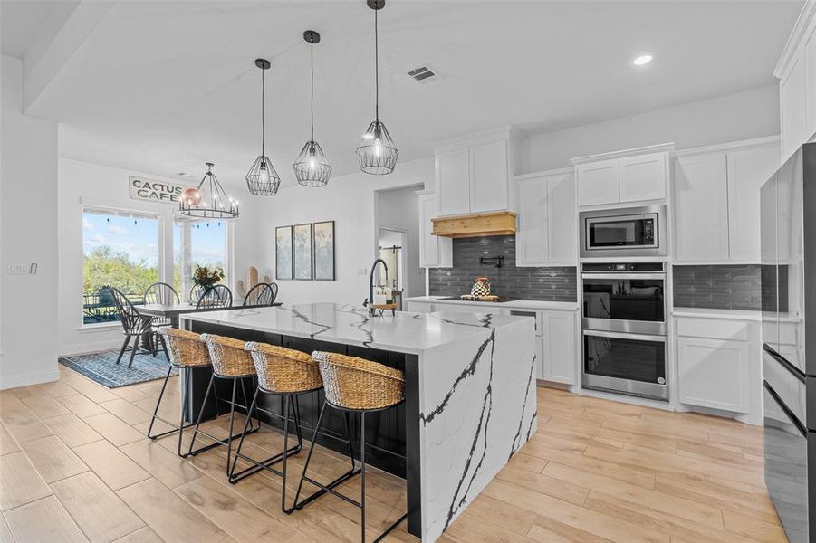 Kitchen with an inviting chandelier, white cabinets, a spacious island, and light wood-type flooring