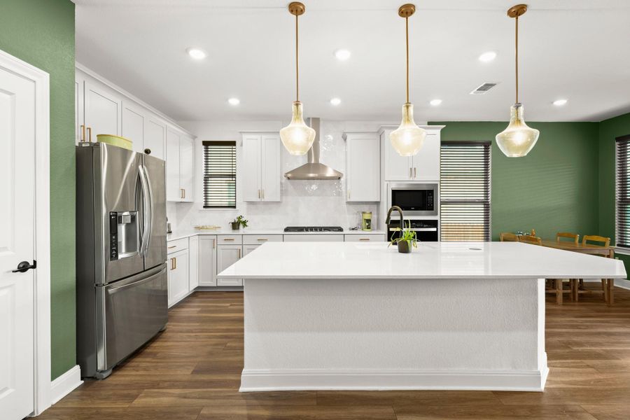 Kitchen featuring white cabinetry, appliances with stainless steel finishes, decorative backsplash, dark wood-type flooring, and decorative light fixtures Kitchen featuring white cabinetry, appliances with stainless steel finishes, decorative backsplash, dark wood-type flooring, and decorative light fixtures