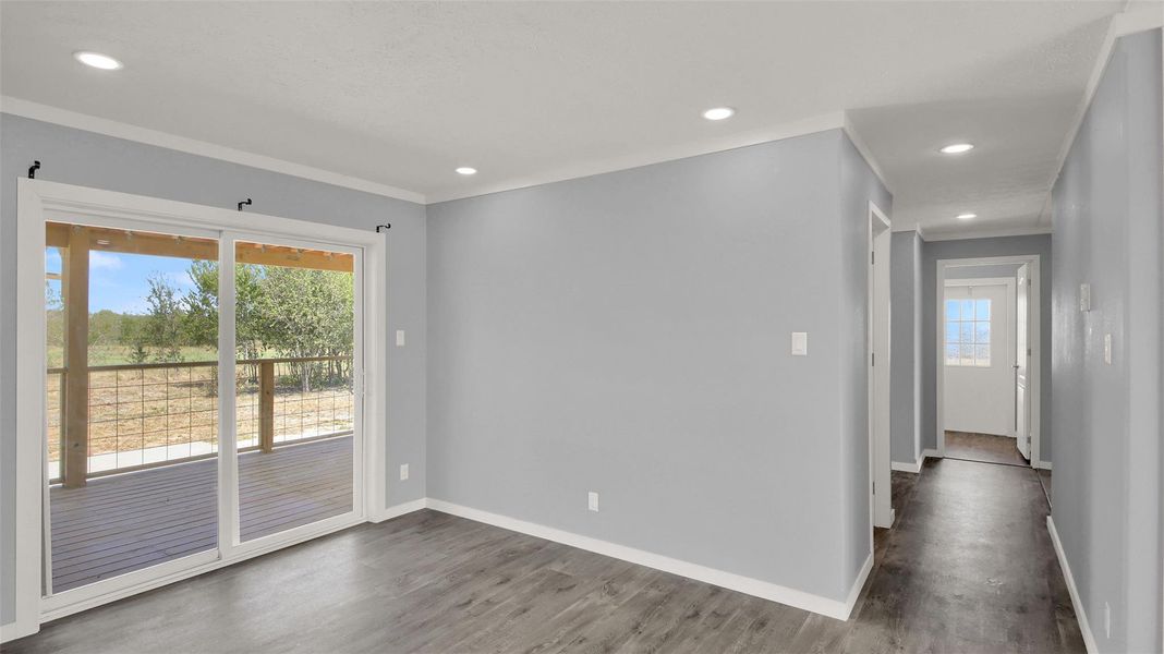 Recessed lighting and wood-look flooring guide the eye from the living area into the hallway.