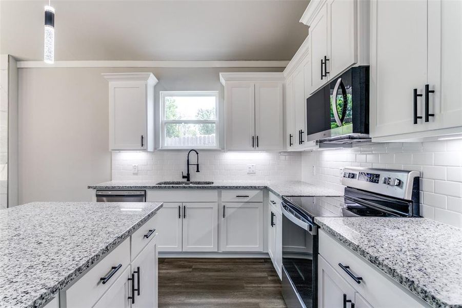 Kitchen with white cabinets, dark hardwood / wood-style floors, appliances with stainless steel finishes, decorative backsplash, and sink