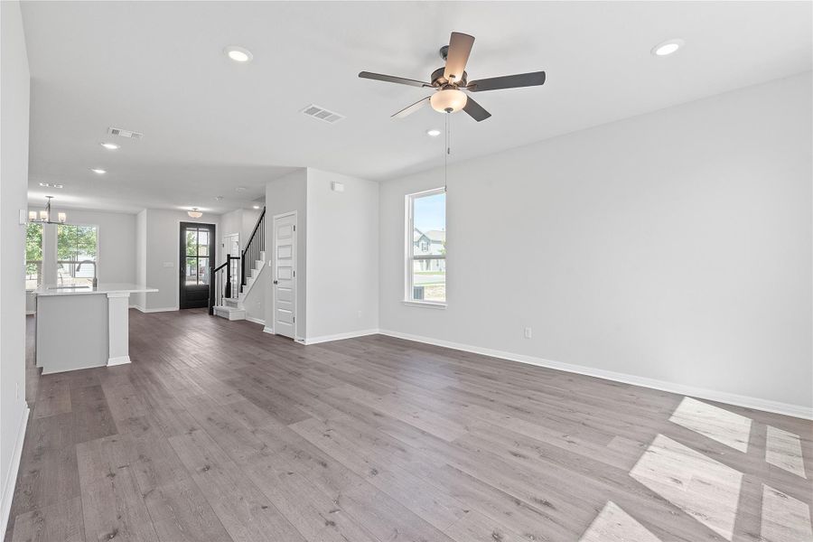 Unfurnished living room featuring recessed lighting, wood finished floors, a ceiling fan, stairs, and a chandelier