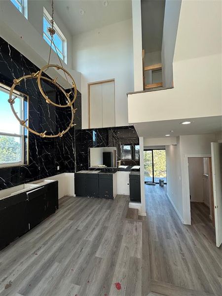 Kitchen featuring a high ceiling, light wood finished floors, recessed lighting, dark cabinets, and decorative backsplash