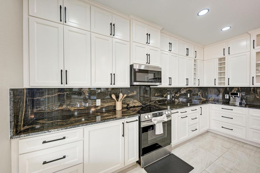 Premium dark granite countertops pair beautifully with crisp white cabinetry in this modern kitchen. Premium dark granite countertops pair beautifully with crisp white cabinetry in this modern kitchen.