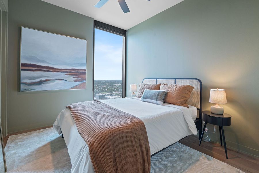 Representative Photo. Secondary Bedroom with wood flooring, large window, ceiling fan, and window treatments included
