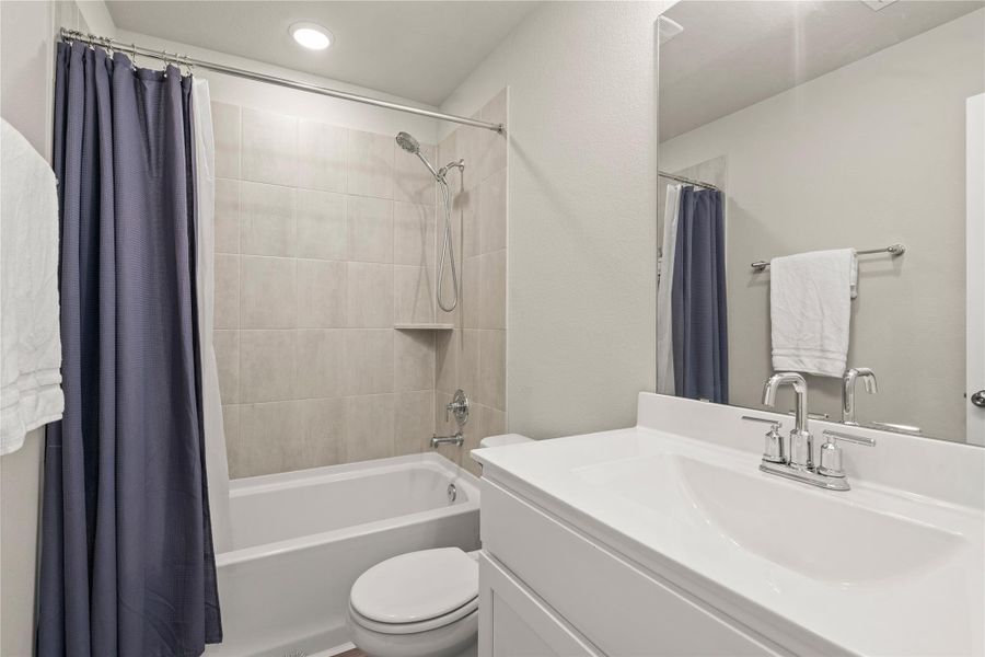 The secondary bathroom features a clean, modern design with a sleek vanity, contemporary fixtures, and a full tub/shower combination with stylish tile surround. Bright finishes and neutral tones create a fresh, inviting space that is perfect for guests or family members. Conveniently located near the secondary bedrooms, this bathroom offers both functionality and comfort with a polished, move-in-ready feel.