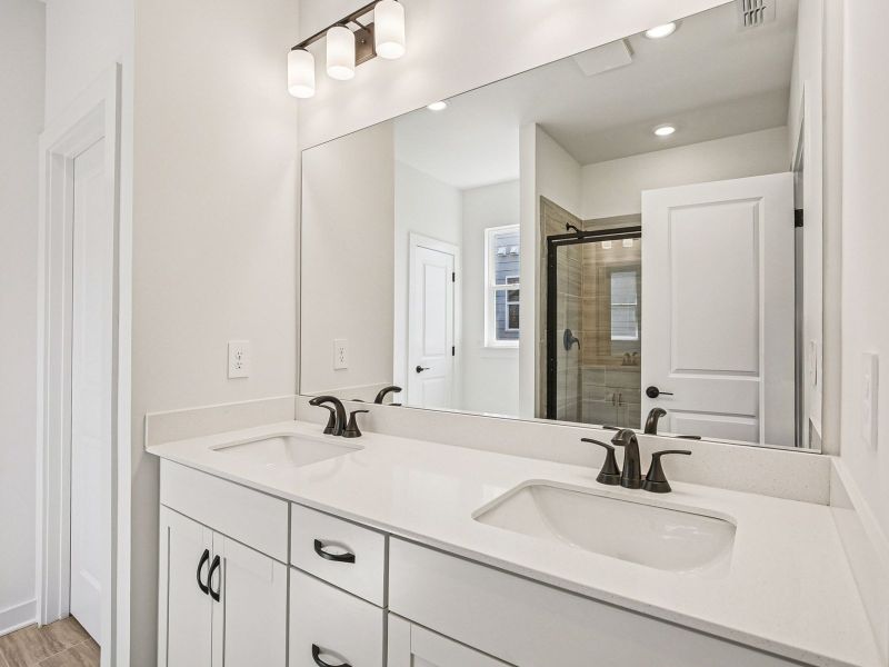 The primary bathroom offers dual vanity sinks and a walk-in shower.