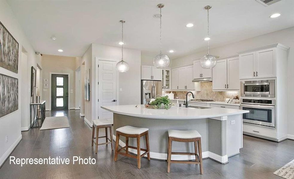 Kitchen with sink, stainless steel appliances, decorative light fixtures, a center island with sink, and white cabinets