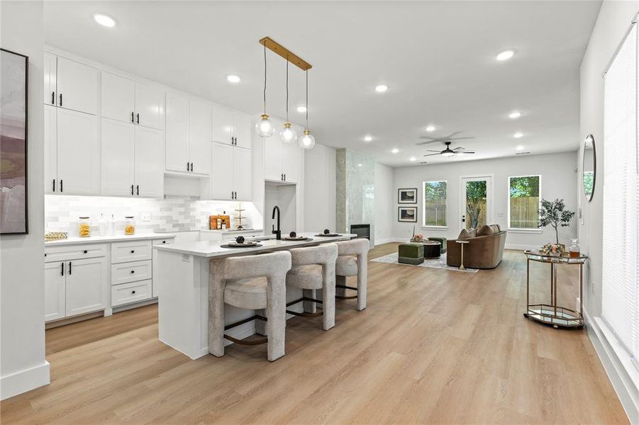 Kitchen featuring hanging light fixtures, white cabinets, tasteful backsplash, a breakfast bar area, and recessed lighting Kitchen featuring hanging light fixtures, white cabinets, tasteful backsplash, a breakfast bar area, and recessed lighting