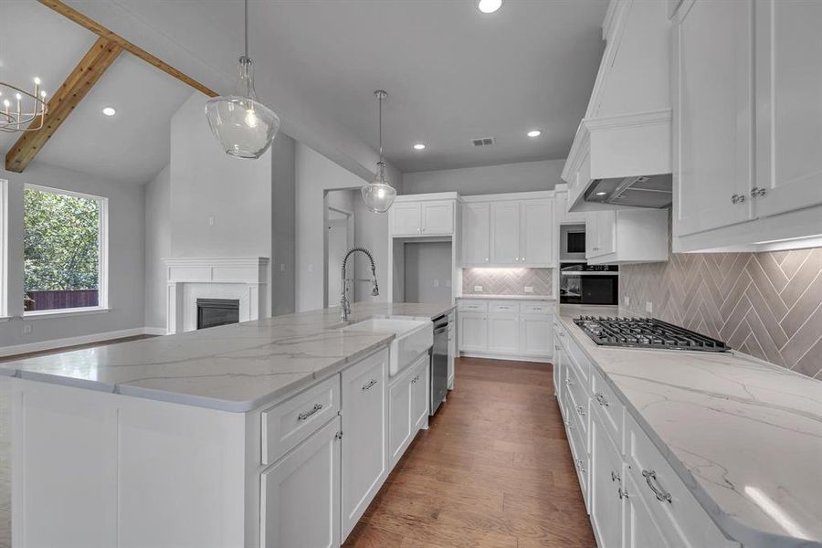 Kitchen featuring light stone countertops, stainless steel appliances, sink, an island with sink, and beam ceiling