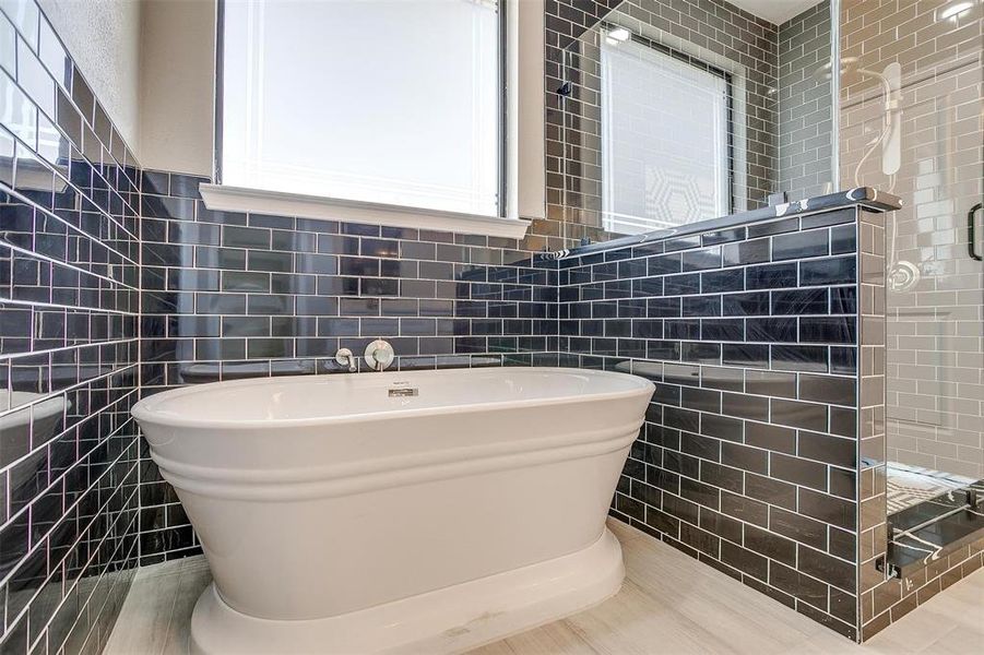 Bathroom with tile patterned floors, tile walls, and a tub